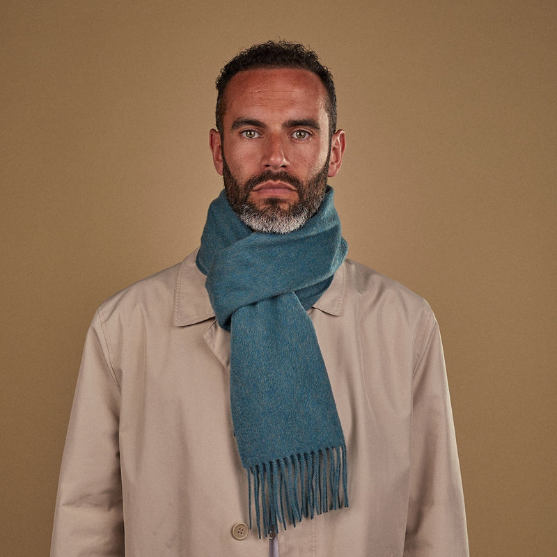 Man wearing Soho Scarves' green cashmere scarf in a classic knot. Paired with fawn three-quarter length coat.