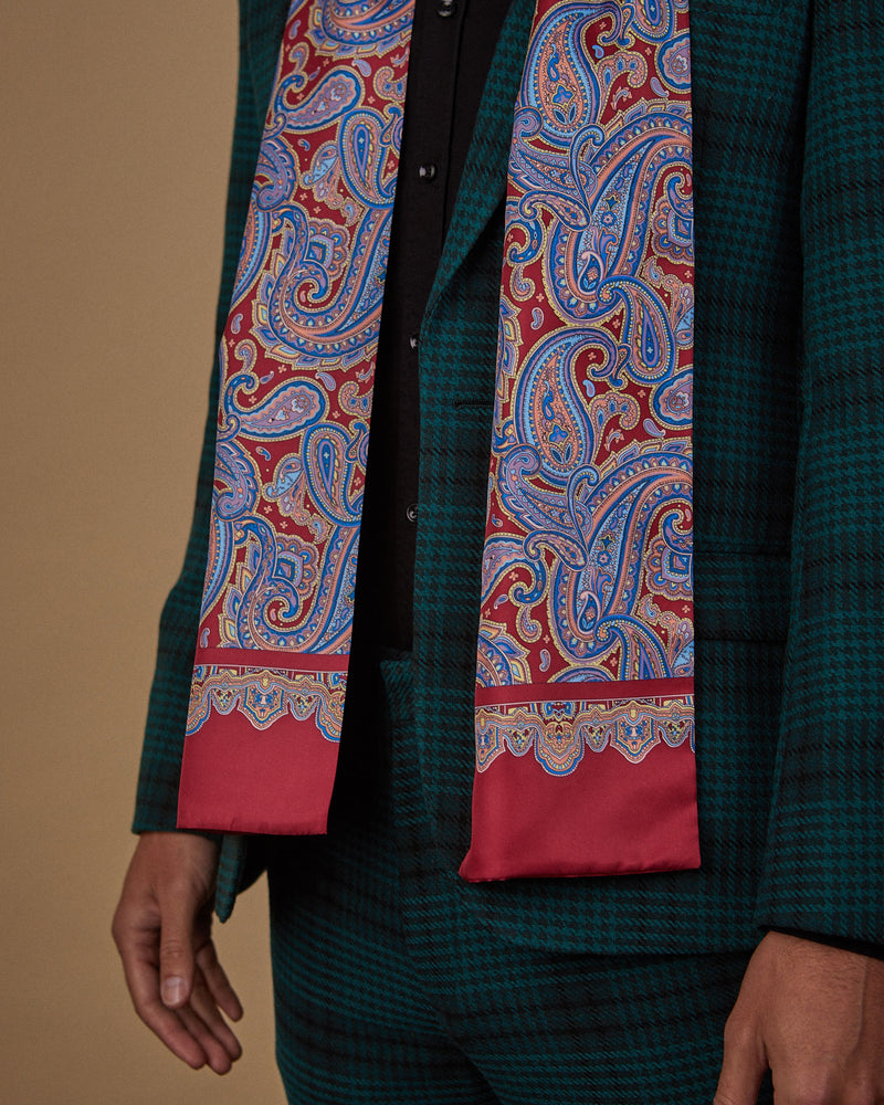 Close up side view wearing a 'Hedge' paisley polyester scarf from SOHO Scarves, clearly showing the blue paisley patterns on a deep red ground.