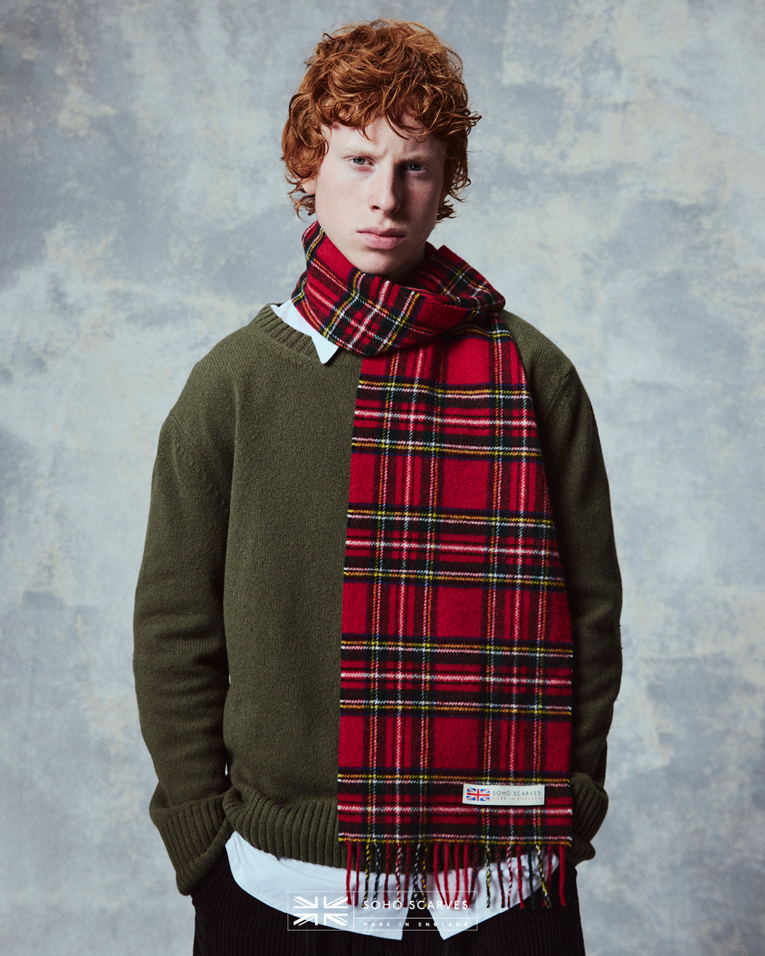 Top-half view of man wearing the Yorkshire-made, 'Highlands Tartan in Red' wool scarf, showing the blue, green, yellow and red tartan pattern.
