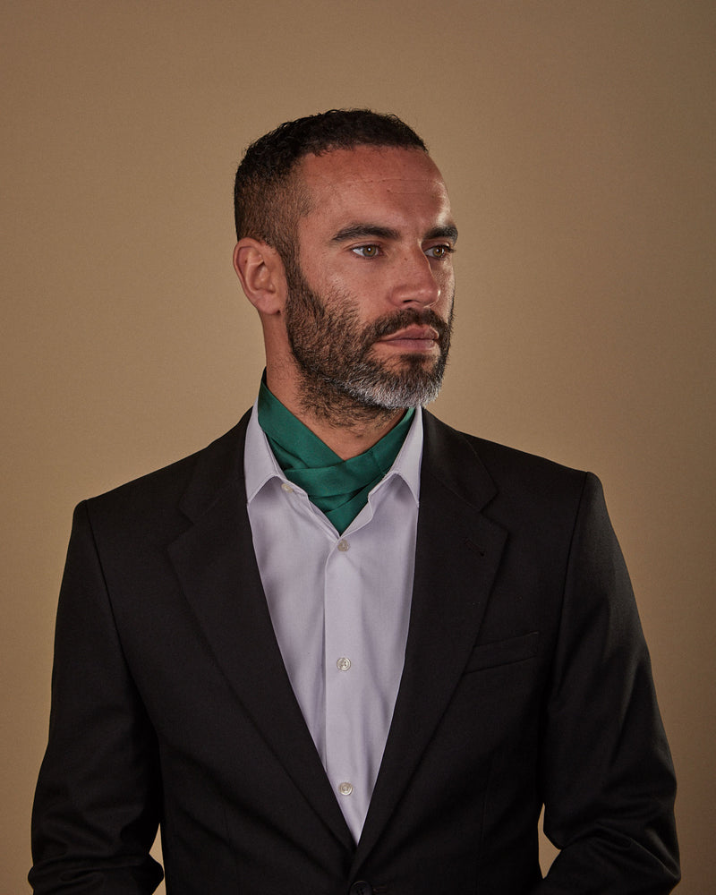 Model looking to his left, wearing plain green 'Ibiza' single pointed Ascot tie. Neatly tucked under white shirt and paired with charcoal jacket.