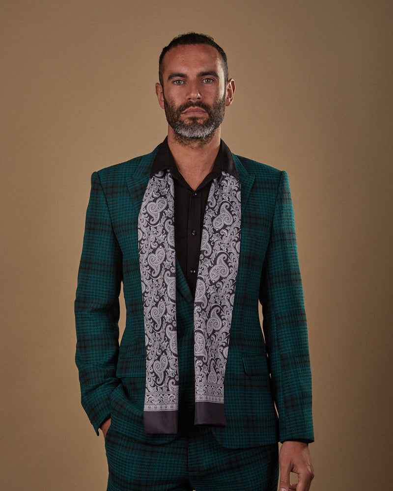 Front view wearing a 'Jaspar' paisley silk scarf from SOHO Scarves, paired with a black shirt and deep green chequered suit.