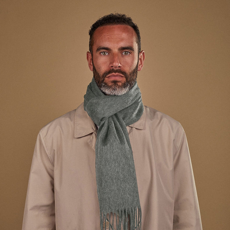 Man wearing Soho Scarves' light-grey cashmere scarf in a classic knot. Paired with fawn three-quarter length coat.