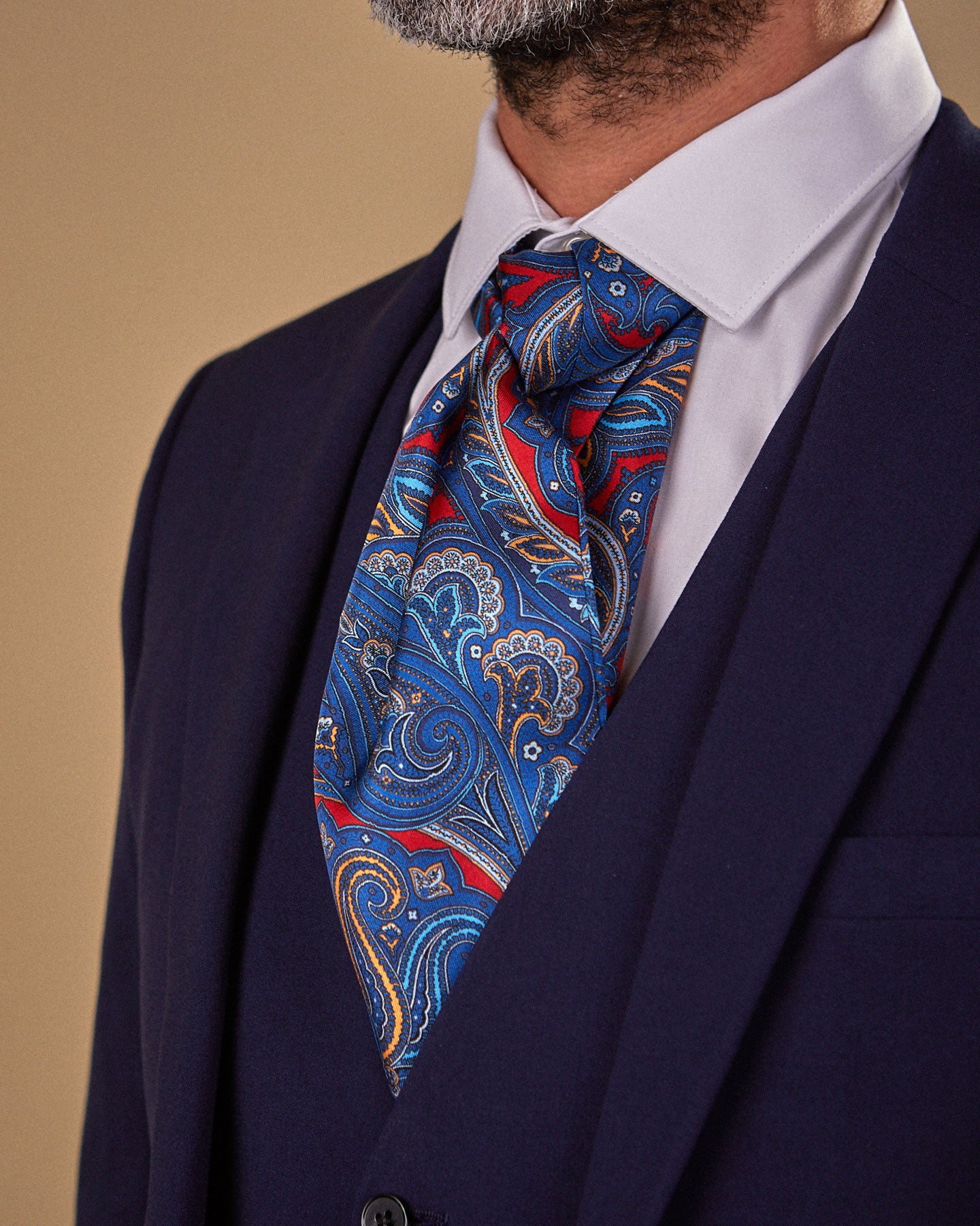 Close up side view wearing an Oxford silk Double Ascot tie from SOHO Scarves, clearly showing the swirls of paisley on a vermillion ground.