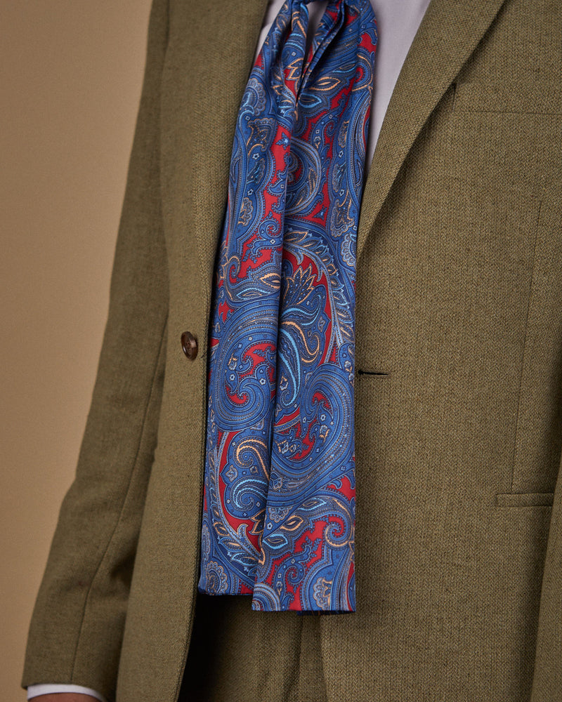 Close up side view wearing a 'Oxford' paisley polyester scarf from SOHO Scarves, clearly showing the deep red fabric with blue paisley patterns.