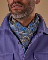 Close-up view of model wearing 'The Piccadilly' wool-silk dress scarf sitting snugly around neck and tucked under blue-violet shirt.
