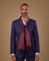 Portrait view of male model wearing 'The Seattle' silk aviator scarf. Tied loosely around neck in a simple knot and paired with a smart, midnight-blue suit.