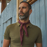 Man wearing 'The Seattle' burgundy and blue geometric bandana. Tied snugly around neck in a simple knot and paired with an olive polo shirt.