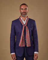 Portrait view of male model wearing 'The Shinjuku' silk scarf. Tied loosely around neck in a simple knot and shoulders and paired with a smart, midnight-blue suit.