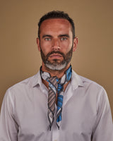 Head and shoulders view of model wearing "The Fan" Japanese inspired silk neckerchief with knot tie at the front. Paired with white shirt.