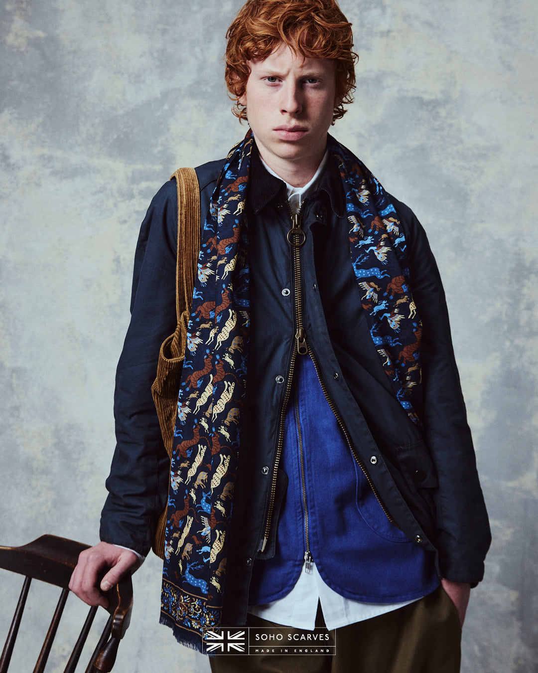 Top-half view of man wearing the English-made, 'Woodland Creatures in Airforce Blue' silk and wool scarf from Soho Scarves.