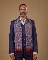 Portrait view of male model looking straight ahead, wearing 'The Vancouver' silk aviator scarf. Draped loosely around shoulders and neck and paired with a smart, midnight-blue suit.