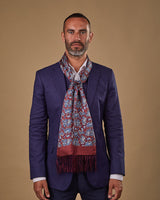 Portrait view of male model wearing 'The Vancouver' silk aviator scarf. Tied loosely around neck in a simple knot and shoulders and paired with a smart, midnight-blue suit.