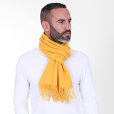Male model looking to his left wearing the bright yellow cashmere scarf from Soho Scarves. Tied snugly around neck in a simple knot and paired with a white sweatshirt.