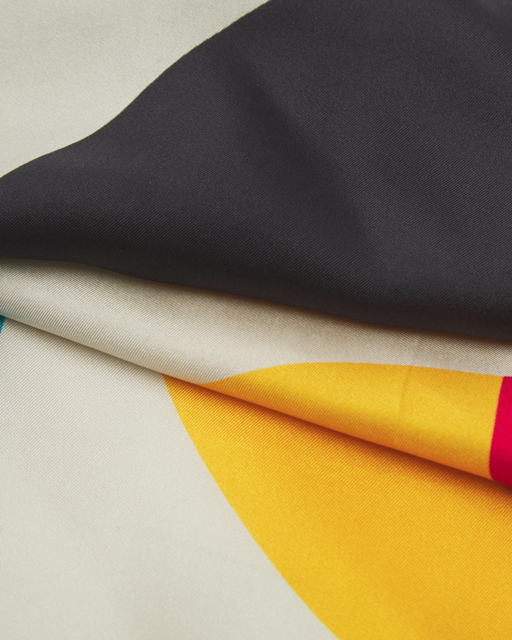 A ruffled close-up of the 'Weimar' silk neckerchief, presenting a closer view of the multicoloured, Bauhaus inspired patterns.