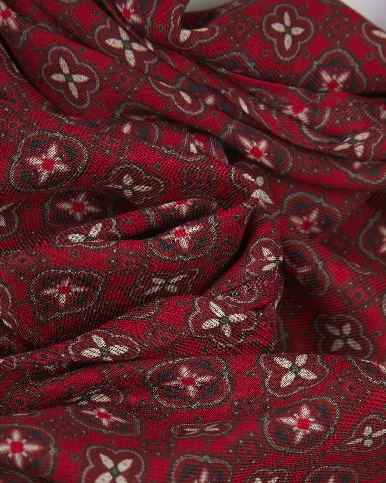 A ruffled close-up of the Wenatchee 'Good Fortune' bohemian wide scarf, showing the soft modal and wool blend fabric with an intricate floral and geometric pattern in varying shades of red with black and cream accents.
