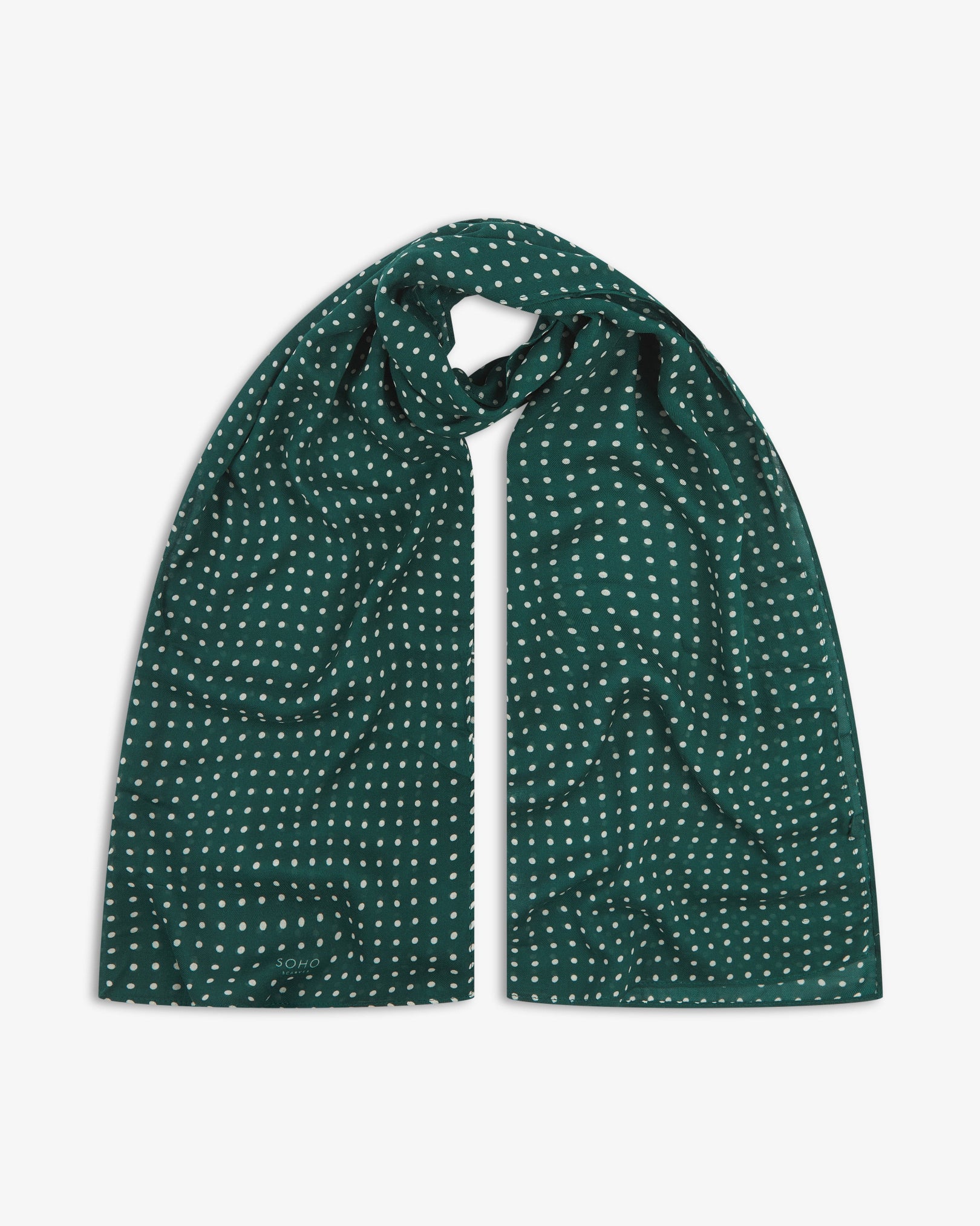 The Westminster RG bohemian wide scarf looped with both ends parallel, showcasing a classic pattern of white polka dots on a British racing green background across the soft modal and wool blend fabric.