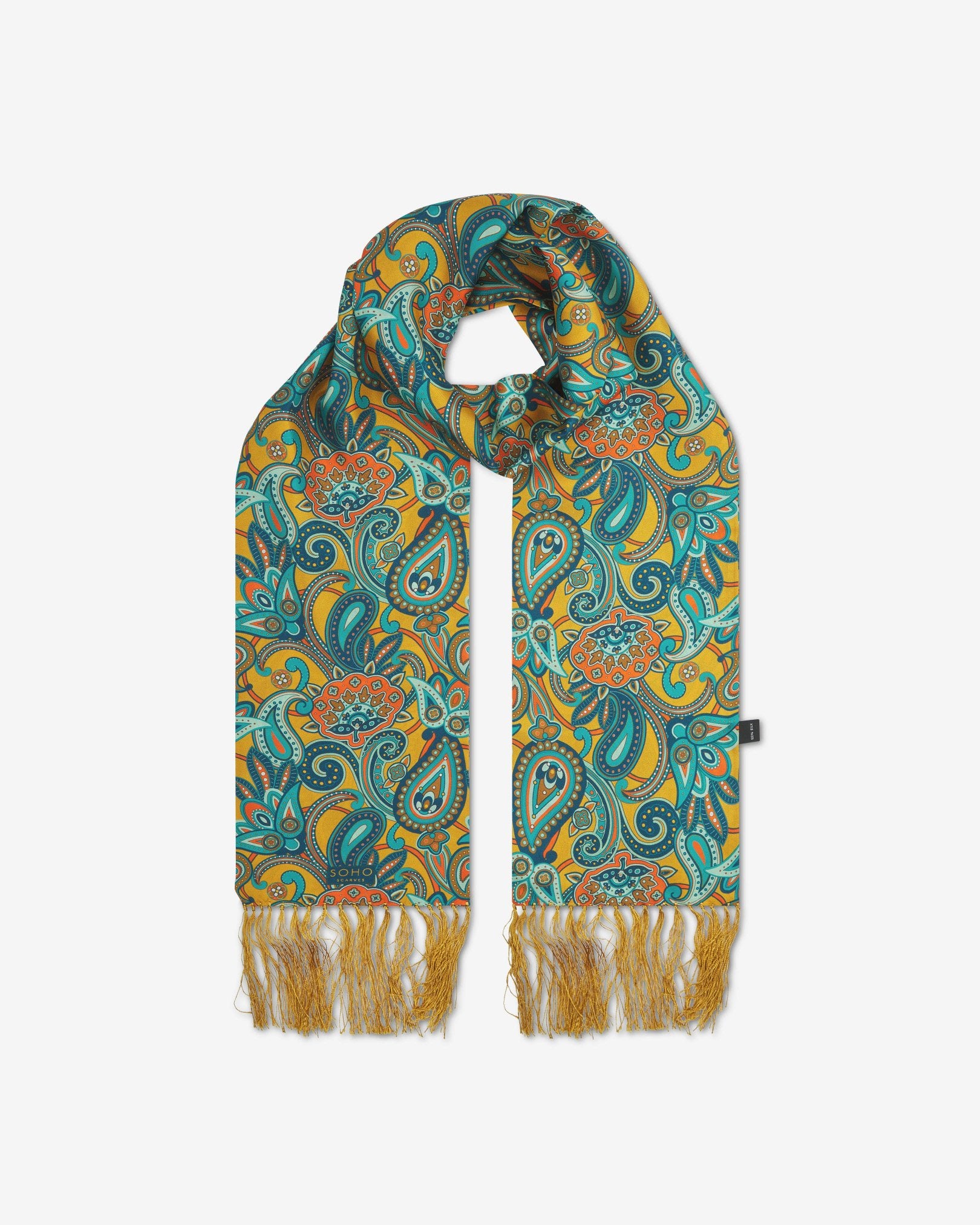 The 'Windermere' gold silk aviator scarf looped with both ends parallel to effectively display the full repeat pattern of blue, blue-green, orange, and yellow paisley patterns on an gold background with matching fringes.