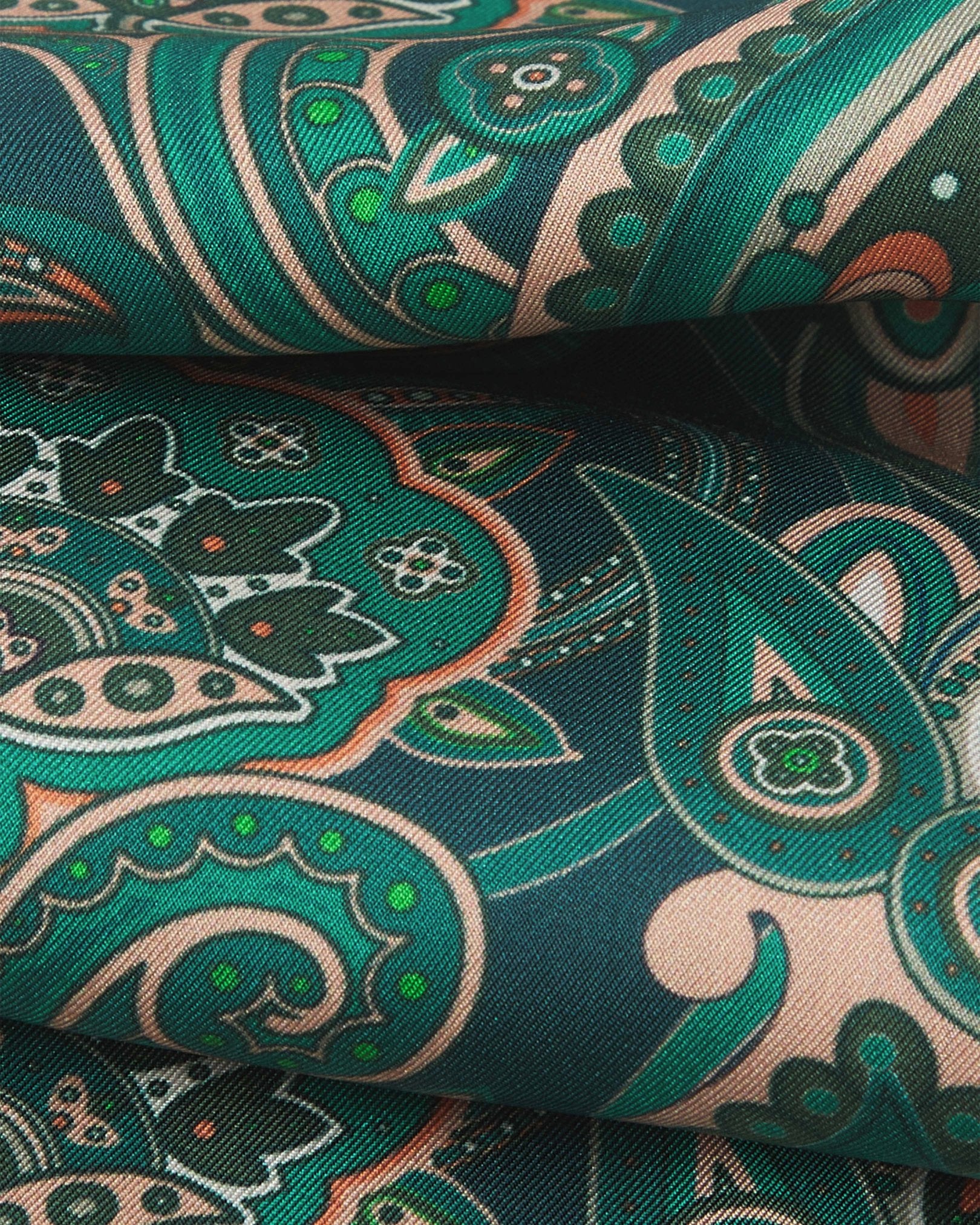 A ruffled close-up of the 'Windermere' emerald-green silk aviator scarf, presenting the overlapping elements of green and salmon pink paisley patterns.