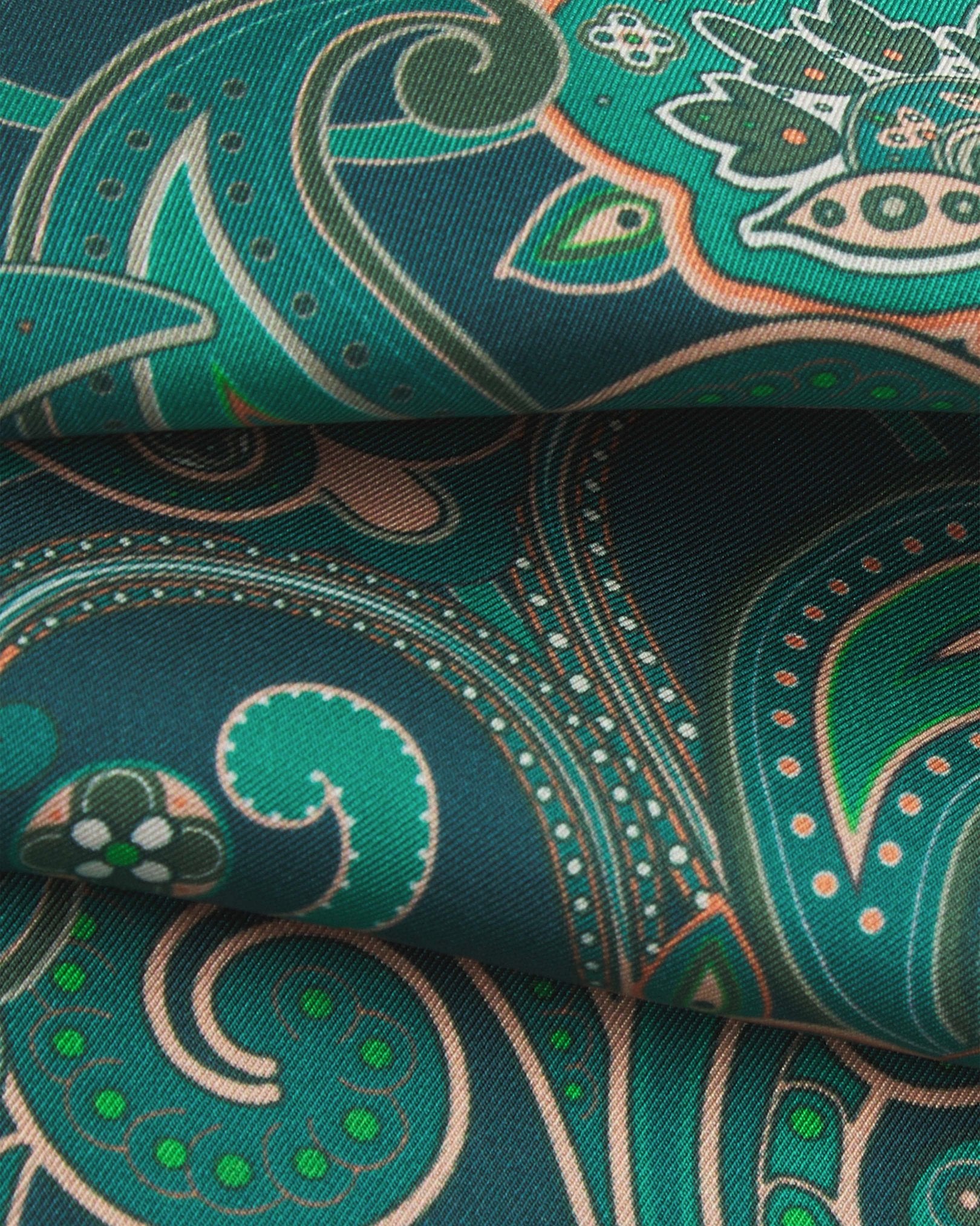 A ruffled close-up of the 'Windermere' emerald-green silk scarf, presenting the overlapping elements of green and salmon pink paisley patterns.