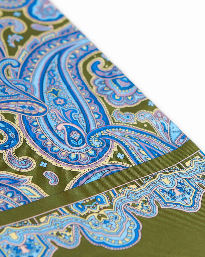 Angled view of the blue paisley patterns complemented with lilac and cream highlights on the dull green coloured dress scarf, with a focus on the ornate border pattern in the foreground.