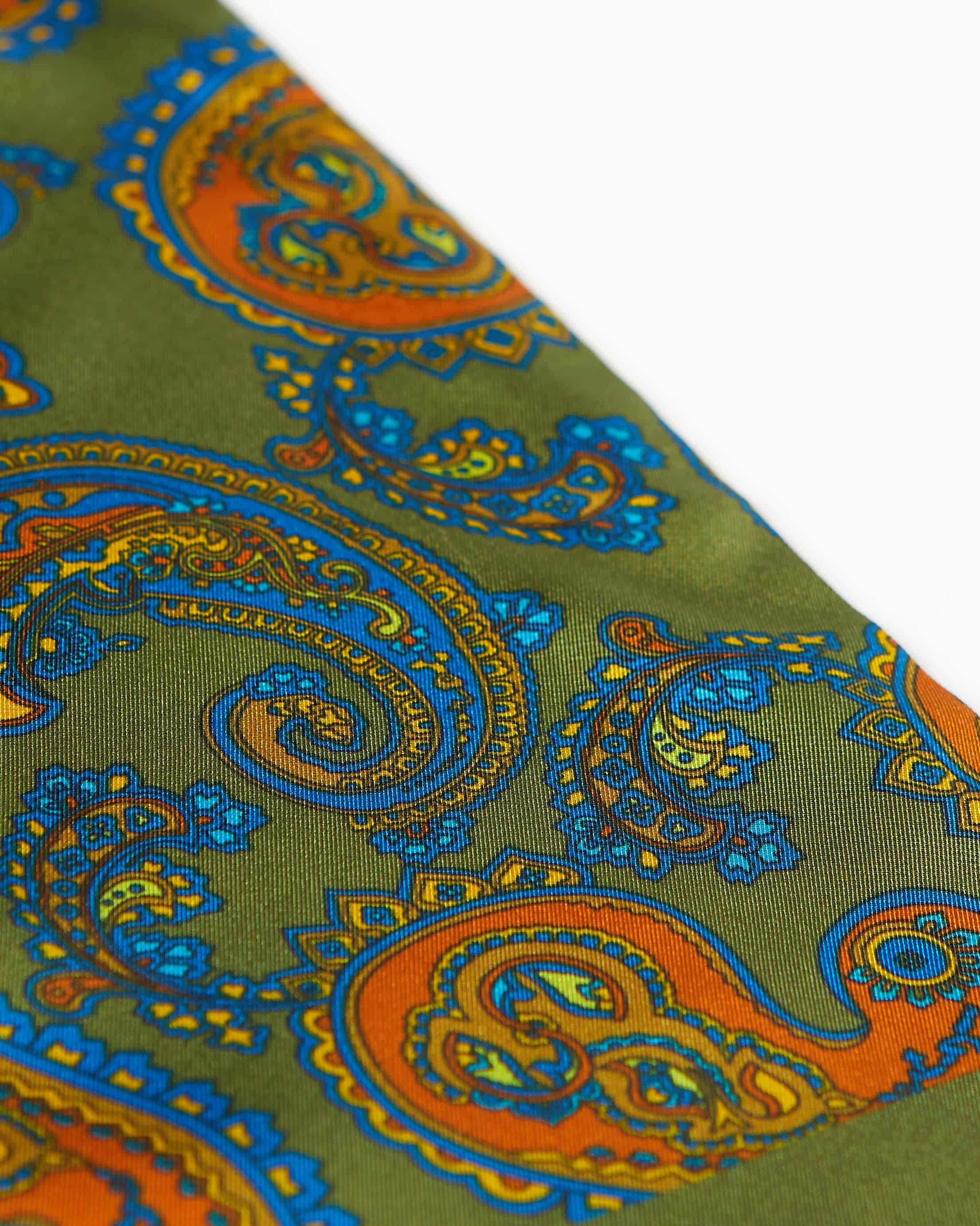 Angled closer view of the deep green silk scarf with focus on the orange paisley patterns and additional blue and gold accents.