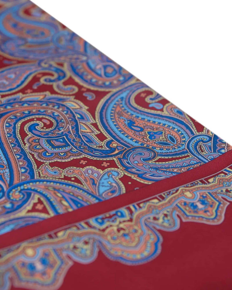 Closer, diagonal angled view of the border and paisley patterns of the Hedge wool-silk scarf.