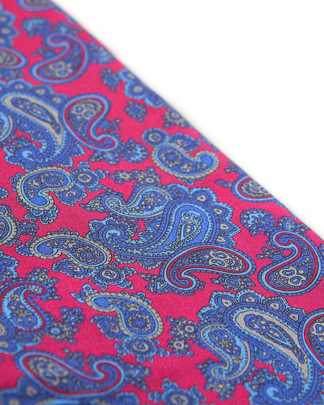 Angled view of the bright pink-red fabric with blue paisley patterns highlighted with pale grey accents.