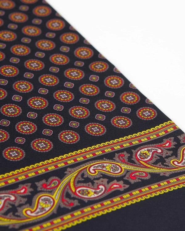 Angled view of the black scarf with yellow-gold, brown and red accents, with a focus on the elegant border pattern.