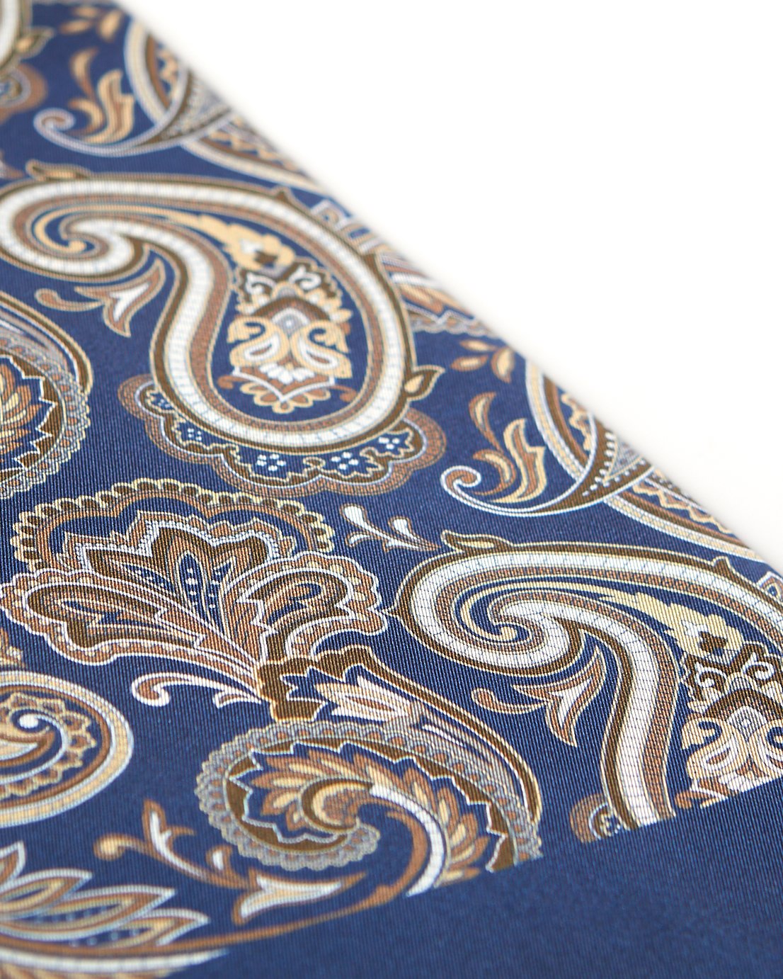 Angled view of the elegant navy blue and gold patterned 100 percent silk scarf, presenting a closer view of the big golden paisley patterns.