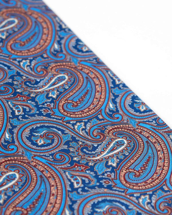 Closer, diagonal angled view of the blue paisley patterns of 'The Sullivan' wool-silk scarf.