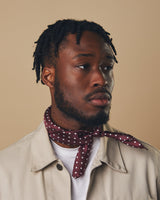 Portrait view of model looking to his left wearing a 'Sapporo' neckerchief with small white dots and tied in a simple knot.