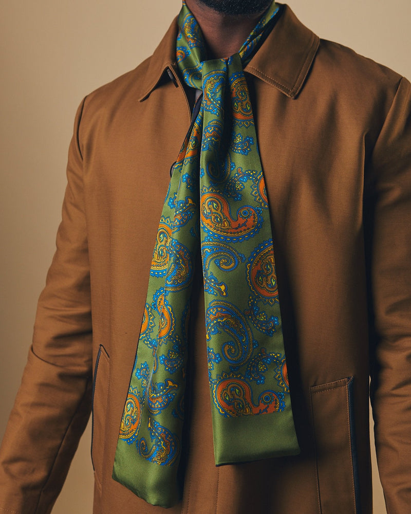 Close up of model wearing 'The Carlisle' rich green wool backed scarf with clear view of multi-coloured paisley patterns and green border tips.