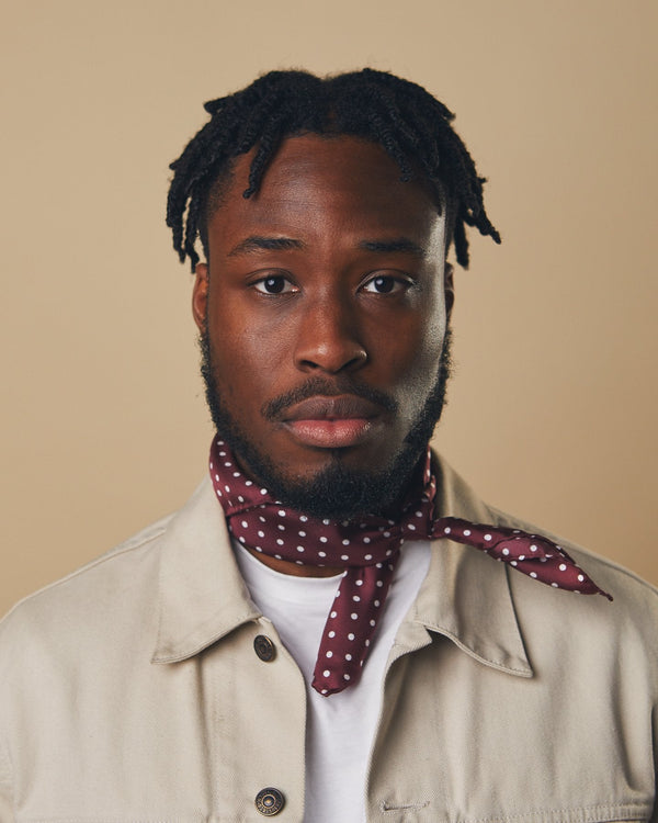 Portrait view of model looking straight ahead, wearing 'The Sapporo' white polka dot neckerchief tied in a simple knot.
