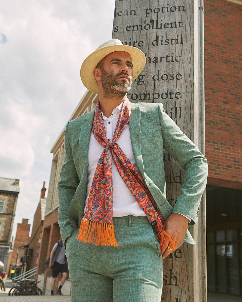 Outdoor top-half shot of model loosely wearing multicoloured floral-paisley 'Ocala' aviator scarf and paired with a mint-green casual suit.