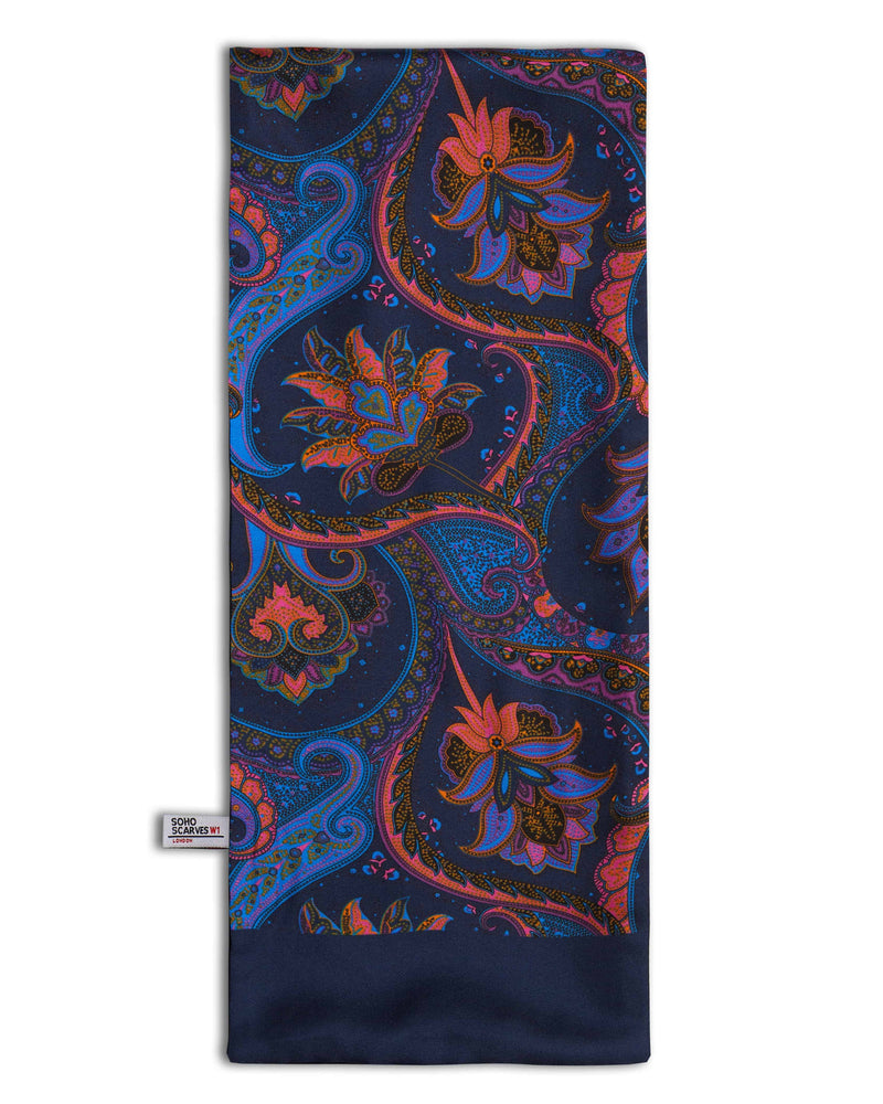 ‘The Kemp’ wool backed scarf arranged in a rectangular shape, clearly showing the multi-coloured paisley patterns, navy blue border and the ‘Soho Scarves’ label on the left edge.