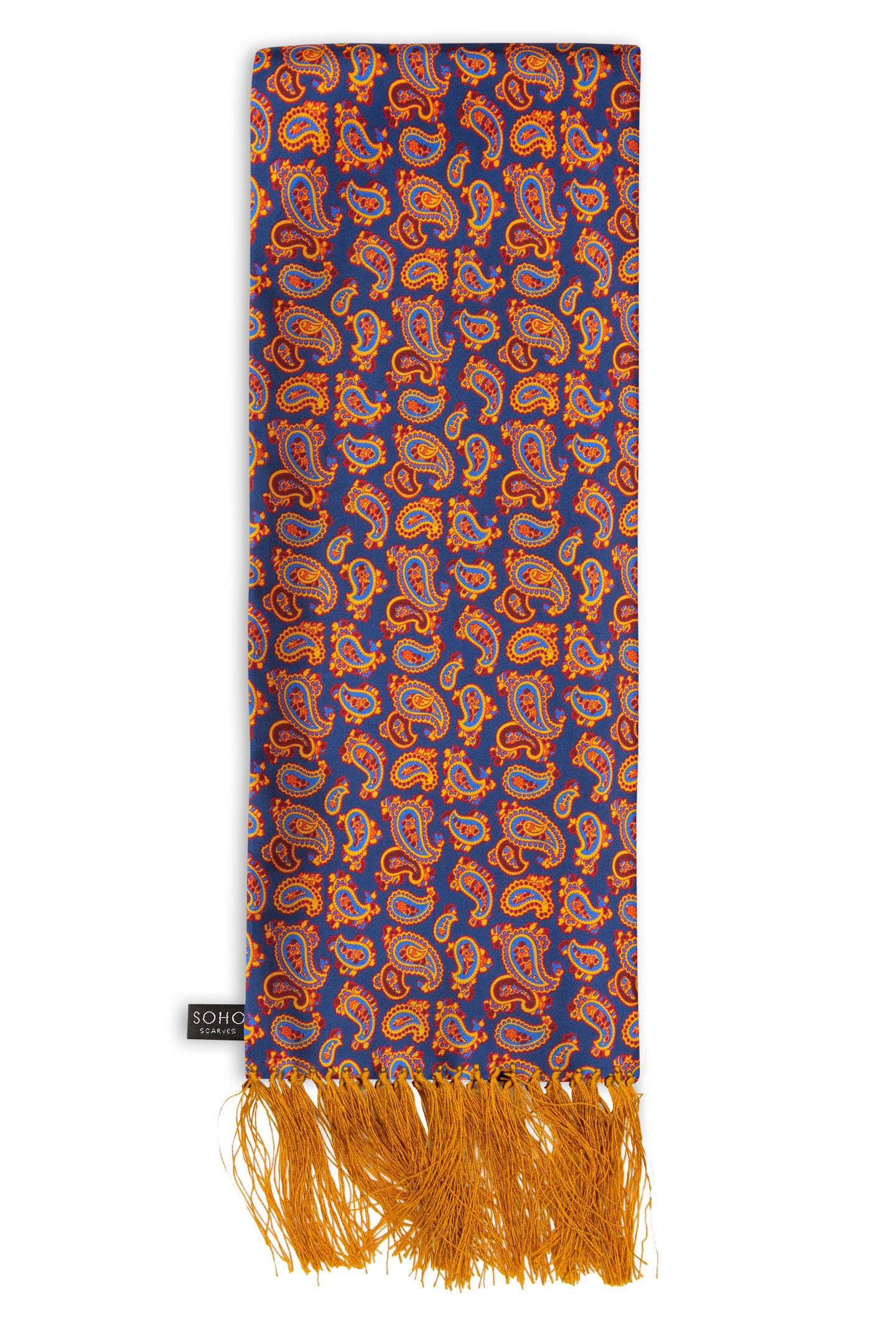 'The Kent Aviator' deep violet/blue silk scarf with small orange, red and royal blue paisley patterns, arranged in a rectangular shape, clearly showing the gold 3-inch fringe and the ‘Soho Scarves’ label on the left edge.