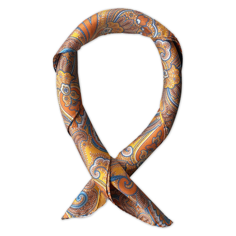 Square scarf rolled into a loop, showing the sheen of the golden yellow neckerchief fabric with vibrant orange, brown and blue paisley patterns.